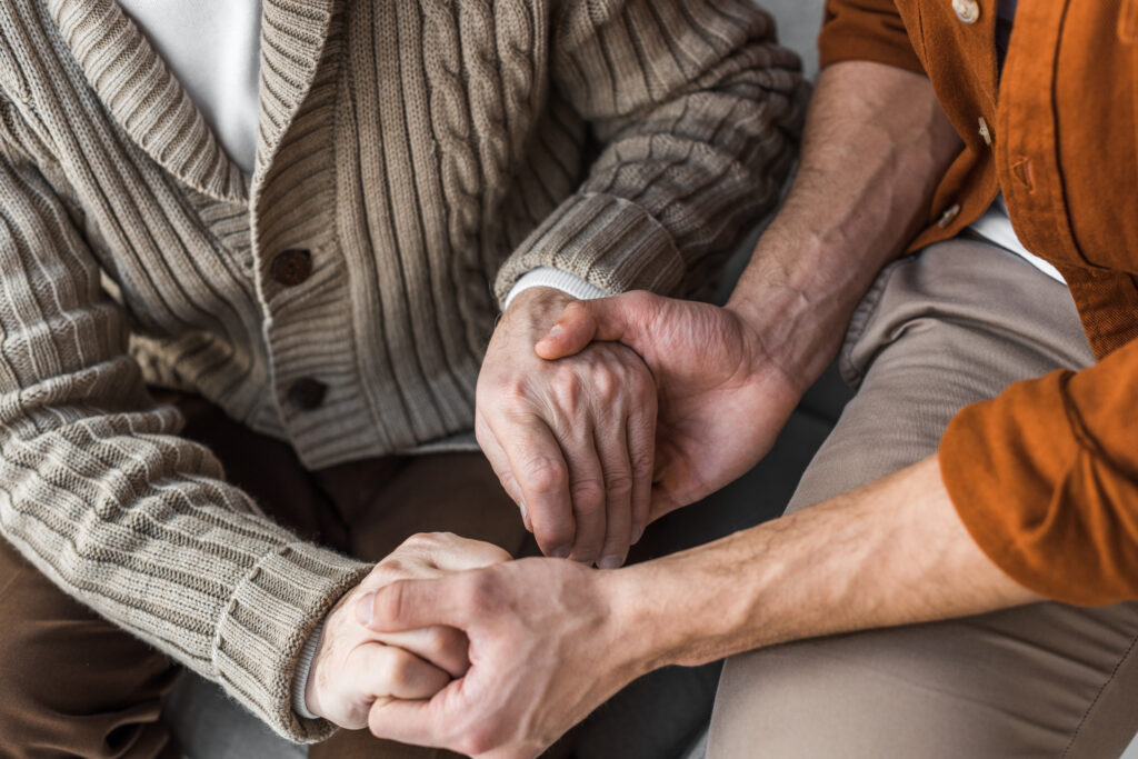 cropped view of senior father and son holding hands