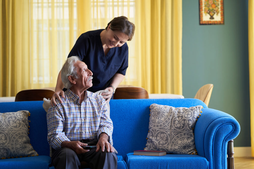 Professional helpful caregiver and a senior man during home visit