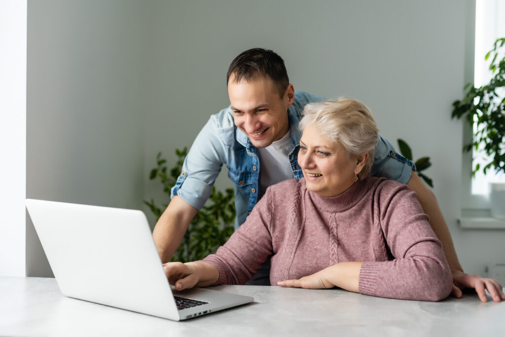 Portrait of a senior woman and a man in front of a laptop computer