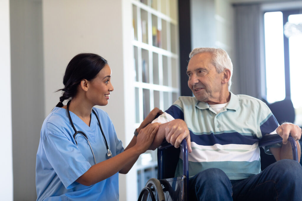 Smiling biracial female physiotherapist talking with caucasian senior